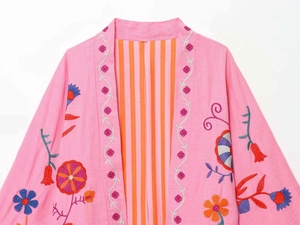 Detail view of colorful floral embroidery and striped lining on pink kaftan cardigan