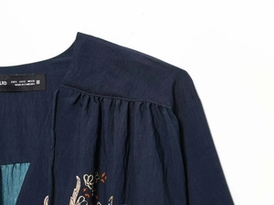 Détail de la blouse ethnique bleu marine montrant la texture tissée et l'étiquette de marque