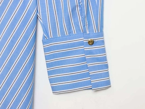 Detail of blue striped shirt cuff with a polished gold circular metal button