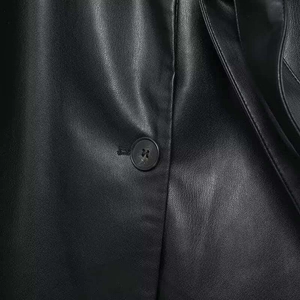 Makroaufnahme von Kunstleder mit feinen Nähten und einem schwarzen Vierloch-Knopfdetail