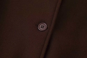 Detail of a dark brown wool coat showing a round button and high-quality fabric texture