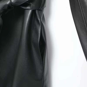 Detail der schwarzen Kunstlederjacke mit Taillenknoten und Seitentaschen-Design