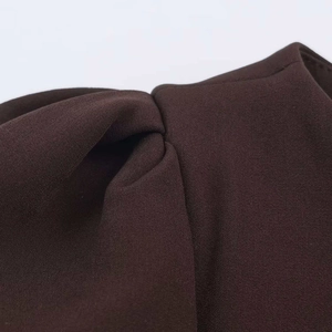 Macro detail of dark brown woven fabric showing precise pleated and knotted design
