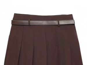 Detailed close-up of dark brown pleated skirt featuring a matching leather belt and fine stitching