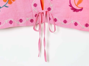 Detail of pink embroidered kaftan featuring floral patterns and lace-up tassel closure