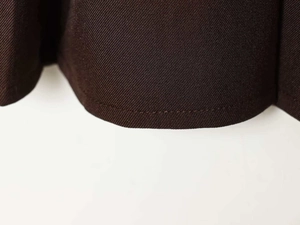 Detailed macro view of dark brown twill fabric texture and neat stitching on high waist skirt