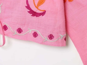 Detailed embroidery on pink linen kaftan featuring floral patterns and intricate stitching