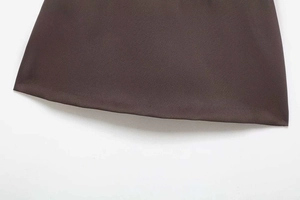 Detailed view of dark brown woven fabric texture and double-stitched hem on mini skirt