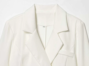 Detailed view of the white blazer notched lapel and size S label with fabric texture