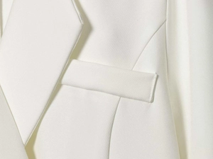 Detailed close-up of white twill fabric texture and tailored lapel on minimal suit jacket