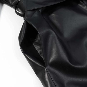 Détail de la poche latérale et du passant de ceinture sur le manteau en cuir noir