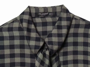 Detail view of the Gingham shirt neckline with Zeal Woman brand label and size tag