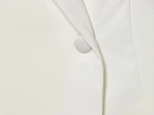 Close-up of white blazer showing fabric-covered button and refined texture
