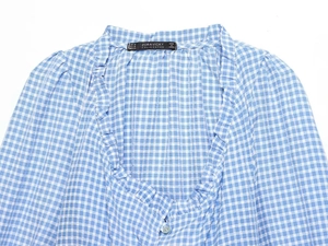 Detail of V-neckline with ruffle trim and buttons on blue and white gingham blouse