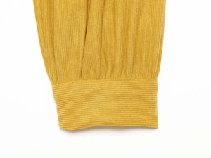 Close-up of yellow ribbed knit texture and striped cuff detail on the cardigan sleeve
