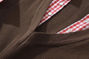 Detail of V-neck ribbed knit top with plaid trim and pearl buttons in British style