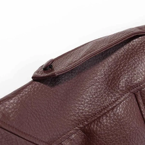 Close-up of burgundy faux leather bomber jacket shoulder with textured grain and buckle