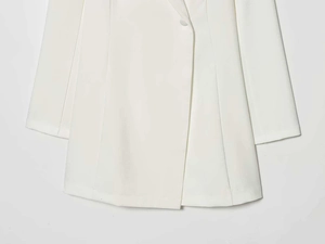 Detail of white minimalist blazer hem with structured stitching and matching button