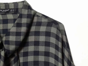 Detailed view of black and green plaid fabric texture and woven brand label on shirt