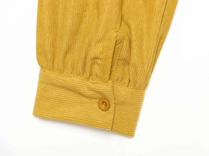 Detail of mustard yellow corduroy sleeve with vertical texture and button closure