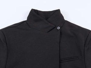 Detail of minimalist black blazer showing asymmetric stand collar and premium fabric texture
