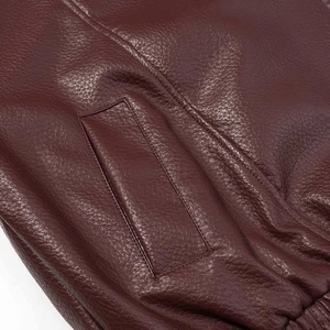 Detail of burgundy leather jacket showing grain texture, side pocket and elastic hem