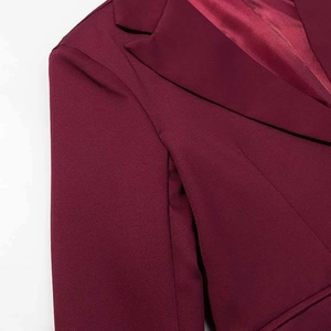 Détail d'un blazer bordeaux avec des épaulettes structurées et une doublure de col en satin