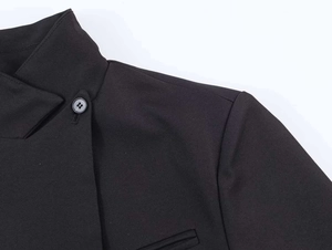 Close-up of black stand-up collar blazer with single button and clean shoulder seams