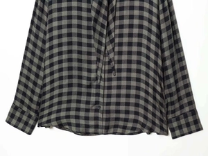 Detail of grey plaid shirt featuring tie-neck ribbon and smooth woven fabric texture