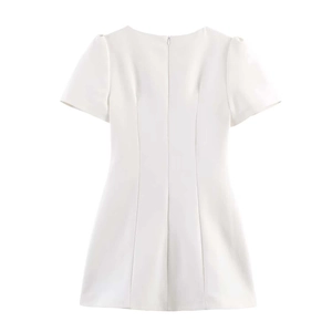 Detail view of the back zipper closure on a white short sleeve pleated dress