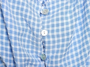 Detail of blue gingham fabric with three iridescent pearl-effect buttons on the shirt