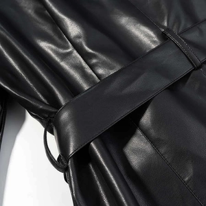 Détails de la ceinture en similicuir noir et des coutures fines sur un manteau élégant pour femme