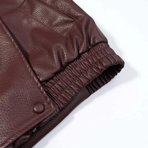 Detail of burgundy leather jacket showing elasticated cuff with button and zipper texture