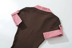 Detail of a brown ribbed knit polo top featuring red gingham collar and sleeve patchwork