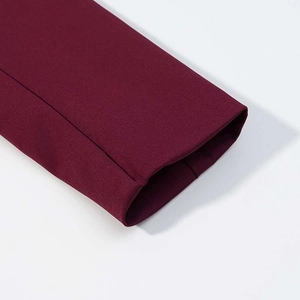 Détail de la manche du tailleur bordeaux montrant les coutures fines et la texture du tissu