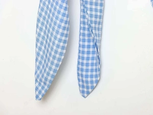 Close-up of blue and white gingham tie strap with fine stitching and pointed end details