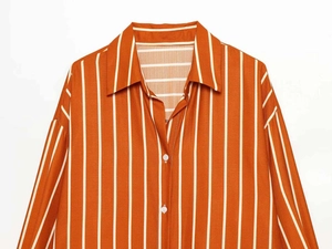 Close-up of orange and white striped shirt collar and white buttons on summer blouse