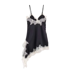 Détail d'une robe nuisette en satin noir avec dentelle blanche délicate et ourlet asymétrique