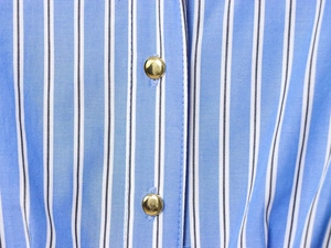 Close-up of blue and white striped shirt dress with polished gold metallic buttons