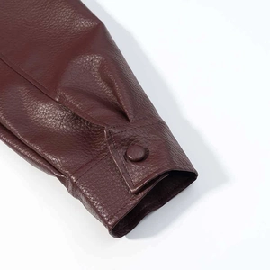 Detailed close-up of dark burgundy faux leather jacket cuff with matching button detail