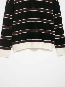 Gros plan d'un pull en maille rayé noir et marron avec ourlet et poignets côtelés blancs