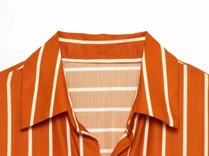 Detail shot of the collar area on a vibrant orange vertical striped long sleeve shirt