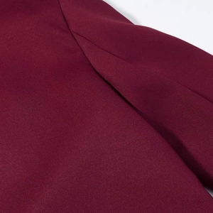 Détail de l'épaule plissée du blazer bordeaux montrant la texture du tissu tissé
