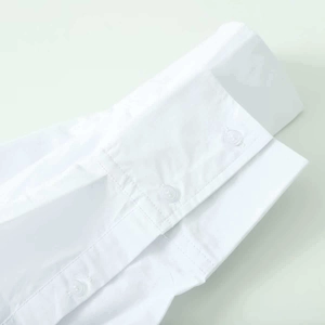 Détail des poignets d'une chemise blanche avec coutures soignées et boutons transparents