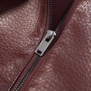 Macro detail of wine red faux leather jacket featuring a textured finish and silver zipper