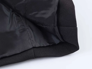 Detailed close-up of a black blazer featuring twill fabric texture and smooth silk lining