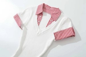 Close-up of white ribbed knit dress with red gingham collar and decorative buttons