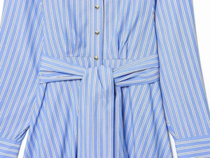 Detailed macro shot of blue striped shirt dress with gold metal buttons and waist tie