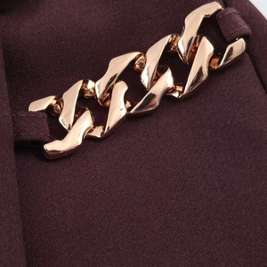 Dettaglio ravvicinato di un tessuto bordeaux a pieghe con una catena in metallo oro rosa
