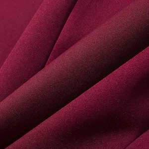 Détail macro d'un tissu tissé bordeaux de haute qualité montrant texture et drapé